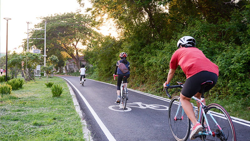 Three cyclists on a dedicated cycle path cycling towards the sunset